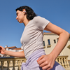 Person stretching outdoors on a balcony with buildings in the background